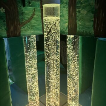 a yellow bubble tube that has two reflections in surrounding mirrors.