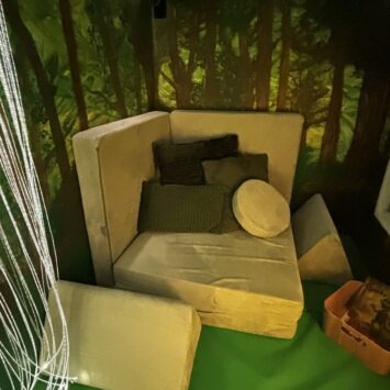 A possum play sofa configured in a seat shape with a variety of cushions on it.