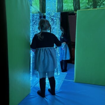 a young girl stand in front of the blue bubble tube
