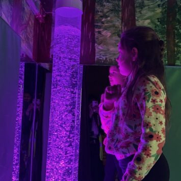 A pre-teen girl stares thoughtfully at the purple bubble tube