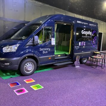 The Goodysphere Sensory bus, parked on a purple carpet at Magna with some sensory tiles on the floor outside as well as a sensory tray in front of the open door.