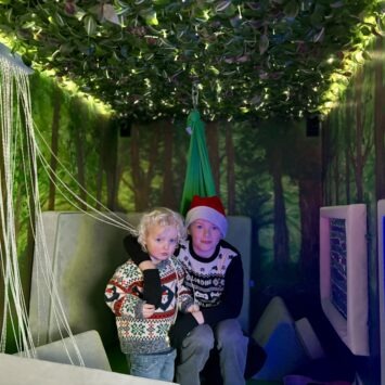 Two brothers smile at the camera from sat on the sofa in the mobile sensory space.