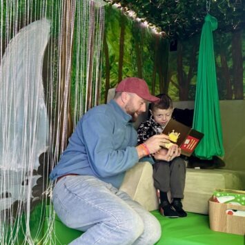 A father plays with his son beside the fibre optic lights inside the mobile sensory room.
