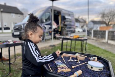 A young boy plays with a music themed sensory tray, the goodysphere sensory bus is blurred in the background creatively.