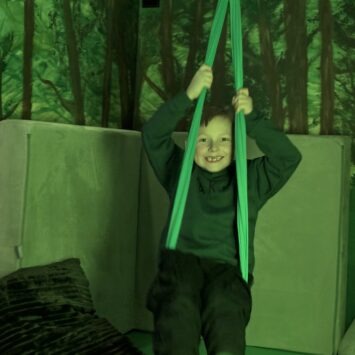 a boy swings in the green sensory swing about the Goodsysphere Sensory bus