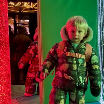 a young boy stands beside a red bubble tube on board the bus