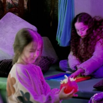 two girls engage separately with sensory toys on board the mobile sensory space.