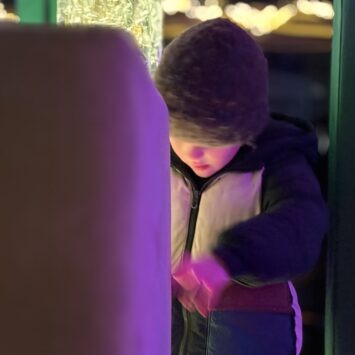 Partly behind a sofa cushion, a young boy glows from the light of the bubble tube
