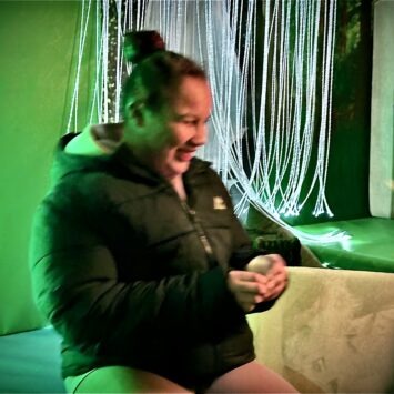 A teenager smiles as she plays with the sensory toys on board the Goodysphere mobile sensory unit