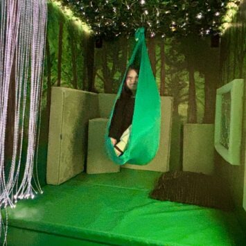 a young adult curls up into a ball in the sensory swing.
