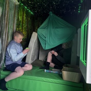two boys build a den under the sensory swing inside the bus