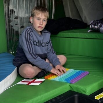 a boy sits in the sensory bus playing with a pop it.