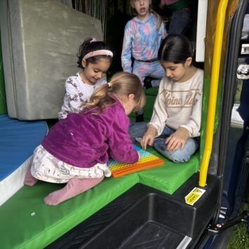 multiple children gather around an extra large pop it on the bus