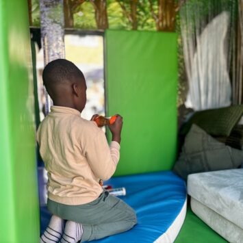 a young boy kneels before the bubble tube enjoying a sensory toy.